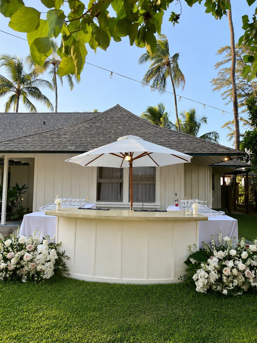 8-foot white bar segment with umbrella and florals at a luxury outdoor event