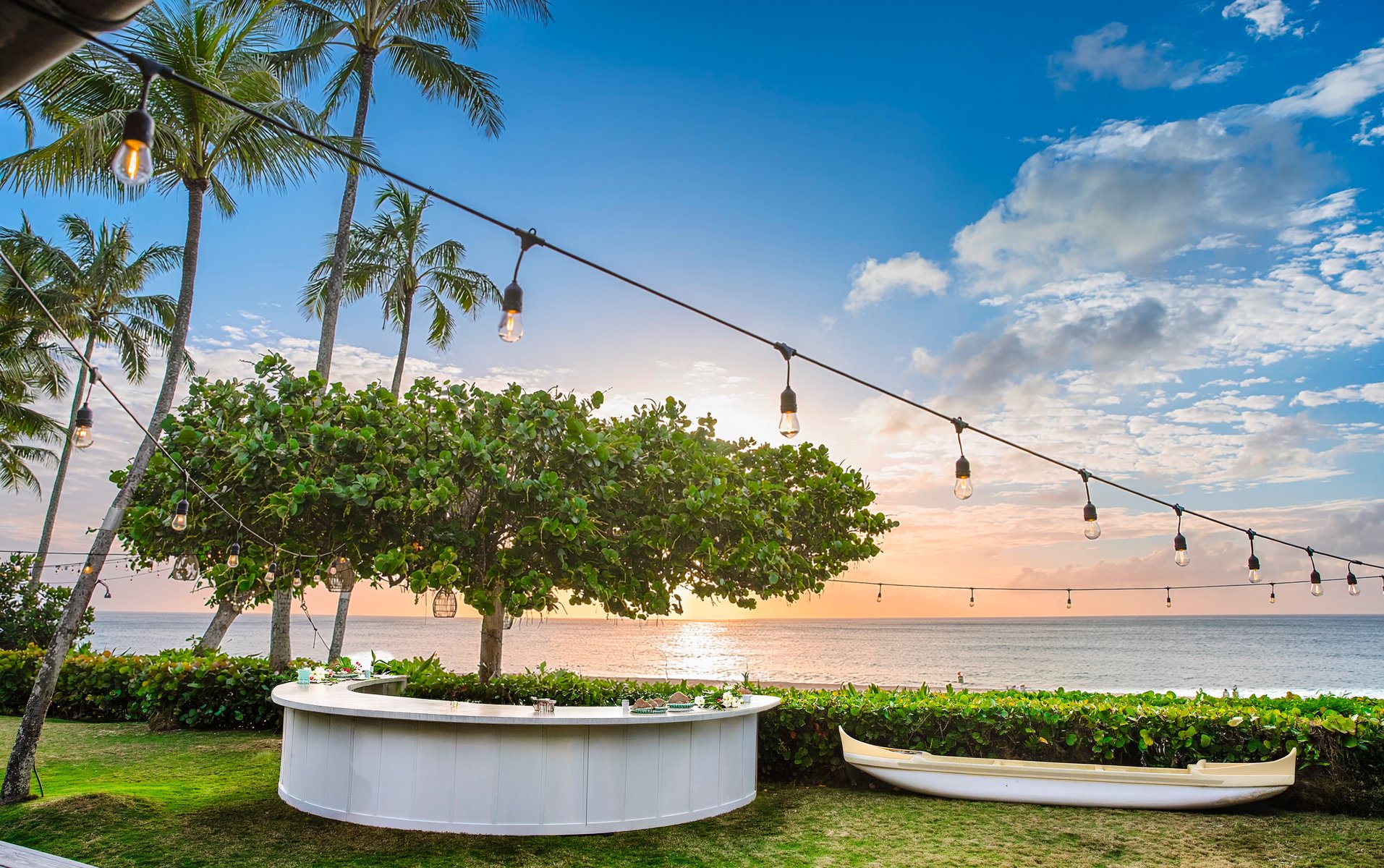 Hawaiian outrigger canoe cooler filled with champagne bottles next to the white circle bar at sunset