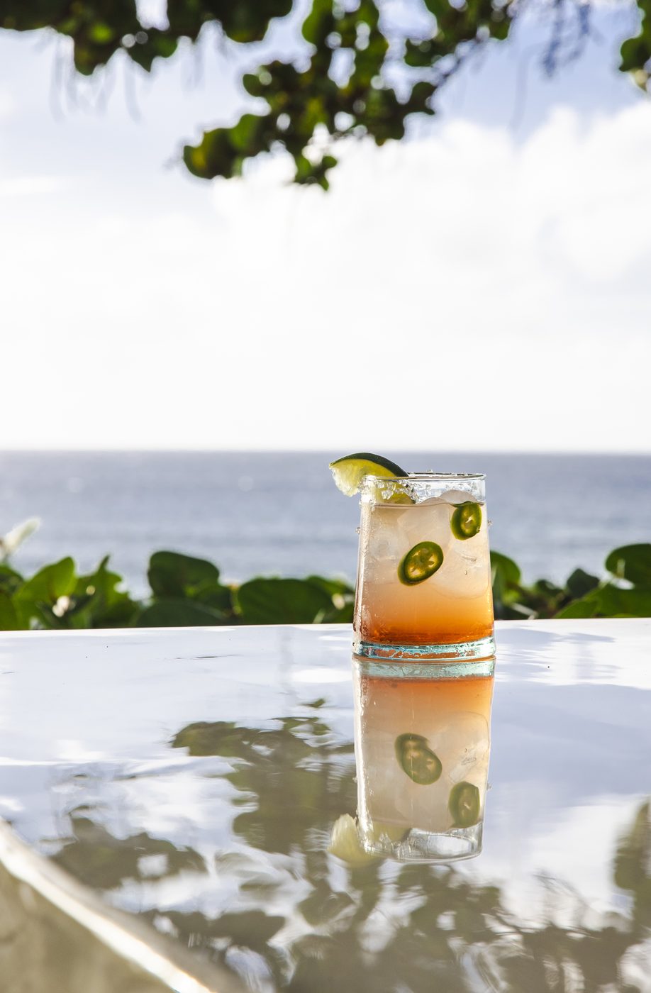 Craft cocktail with jalapeno and lime on polished bar countertop