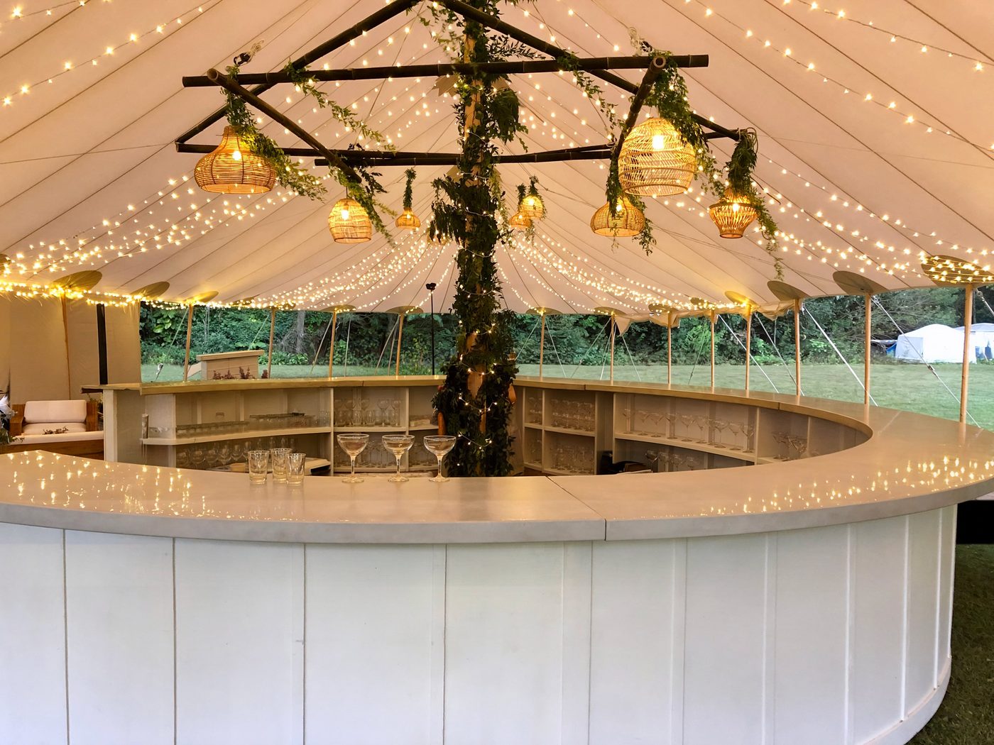 White circle bar fully set up under a clear tent at a luxury wedding
